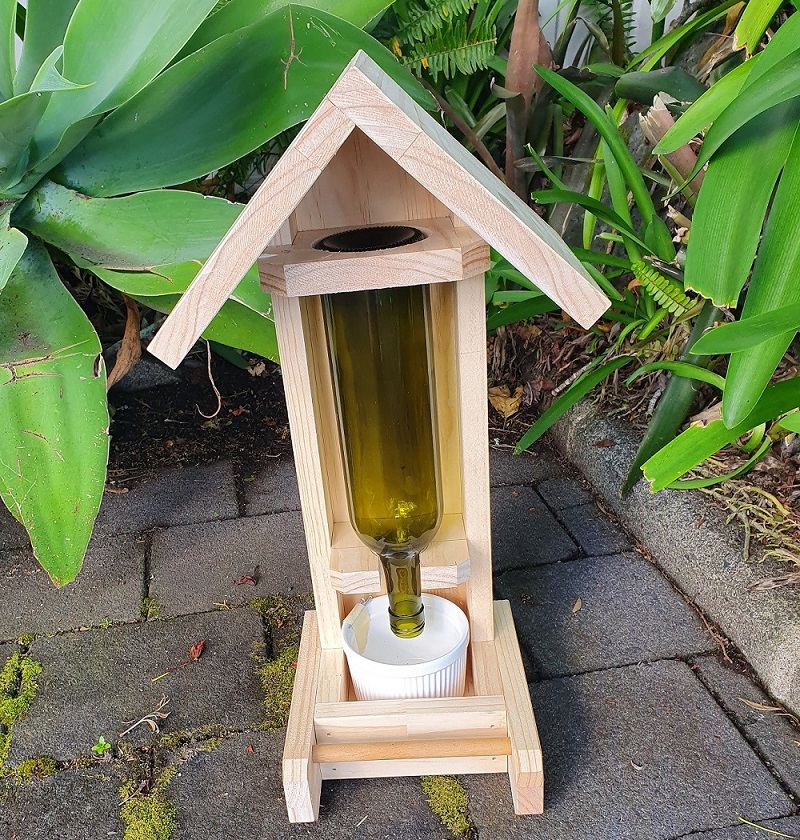 Wooden bird feeder with glass bottle and ceramic seed bowl